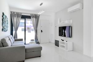 a white living room with a couch and a tv at Apartment Diamante in Pilar de la Horadada