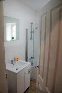 a white bathroom with a sink and a shower at Heritage Apartments in Funchal