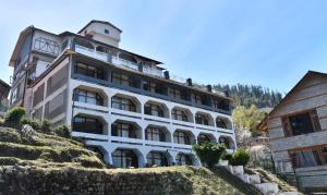 un gran edificio blanco en la cima de una colina en Hotel Snowcrests Manor, en Manali