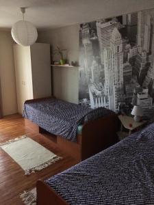 a bedroom with two beds and a city mural on the wall at Apartman Melody in Sombor