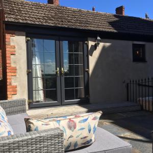 una casa con puertas de cristal y una almohada en el porche en The Stables at the Old Vicarage en Lincoln