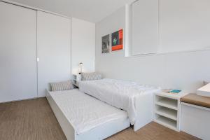 a white bedroom with a bed and a desk at knokkeappart Penthouse 2-3 pers in Knokke-Heist