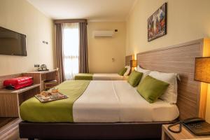 Hotel Roma Sud في فراسكاتي: غرفه فندقيه سريرين وتلفزيون