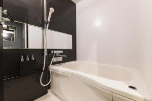 La salle de bains est pourvue d'une baignoire blanche et de murs noirs. dans l'établissement GRAND BASE Mojiko, à Kitakyūshū
