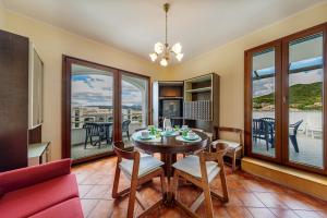 a dining room with a table and chairs and windows at Le Residenze Del Porto in La Caletta