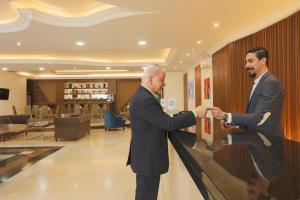 two men in suits shaking hands in a lobby at President Hotel in Jounieh