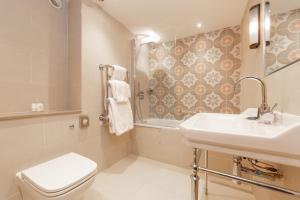 a bathroom with a sink and a toilet and a tub at The Old Cock Inn in Harpenden