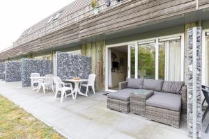 a patio with a couch and a table and chairs at Appartement De Wadloper, Resort Amelander Kaap! in Hollum