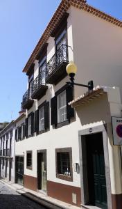 ein weißes Gebäude mit schwarzen Balkonen auf einer Straße in der Unterkunft Heritage Apartments in Funchal
