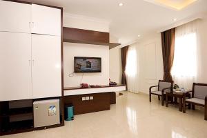 ein Wohnzimmer mit einem TV, einem Sofa und einem Tisch in der Unterkunft Thăng Long Hotel II in Hạ Long