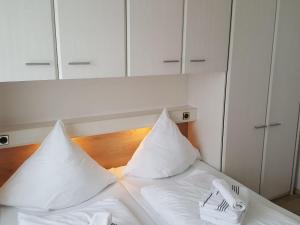 ヴェスターラントにあるSylter-Besserburg-App-16の白い枕とフォーク、ナプキンが備わる白いベッド