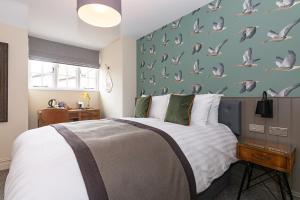 1 dormitorio con cama y pared con palomas en The Old Cock Inn en Harpenden