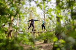 duas pessoas andando em uma ponte suspensa na floresta em Four Seasons Hotel Hampshire em Winchfield