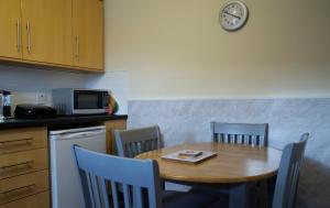 a kitchen with a table and chairs and a clock on the wall at Apartment 1, Phoenix Flats in Portree