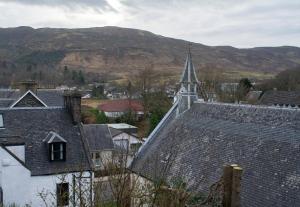 a church with a steeple in a town with mountains at Apartment 1, Phoenix Flats in Portree