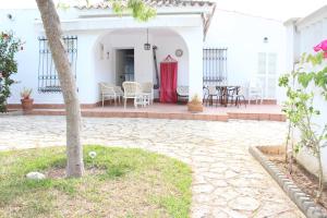 een wit huis met een patio met een tafel en stoelen bij Chalet La Costa in Chiclana de la Frontera