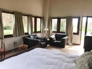 a bedroom with a bed and two chairs and windows at Hameau de Montcabirol - Pyrénées in Mirepoix +29 photos