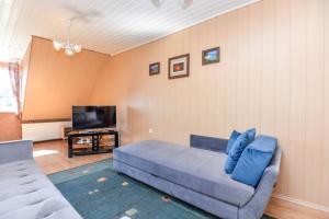 uma sala de estar com um sofá azul e uma televisão em Nida Apartments em Nida