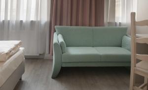 ein grünes Sofa in einem Zimmer mit einem Bett in der Unterkunft Hotel Deutsches Theater in München