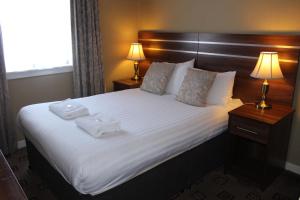 a bedroom with a large bed with two towels on it at Cairn Hotel in Bathgate