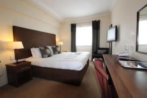 a hotel room with a large bed and a desk at Cairn Hotel in Bathgate