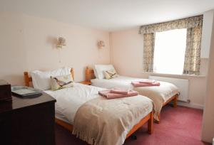 a bedroom with two beds and a desk and a window at Grove Cottage in Yarmouth