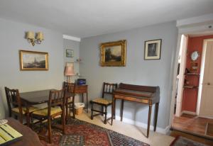 a living room with a table and a piano at Grove Cottage in Yarmouth