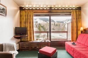 a living room with a red couch and a large window at Résidence Pierre & Vacances Le Mont d'Arbois in Megève