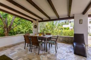 een eetkamer met een tafel en stoelen op een patio bij Molnar Resort Villa Mimoza & Apartment Nea in Brzac