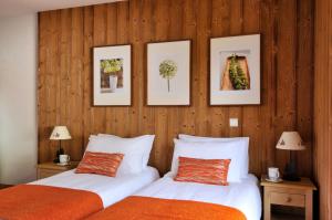 two beds in a room with three pictures on the wall at Savoy Morzine in Morzine