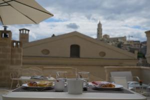 una mesa con 2 platos de comida en el balcón en 5 Elementi Sassi Matera en Matera