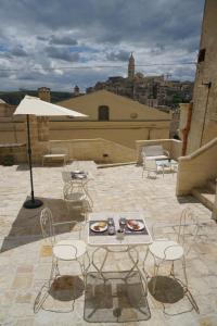 um pátio com uma mesa, cadeiras e um guarda-sol em 5 Elementi Sassi Matera em Matera