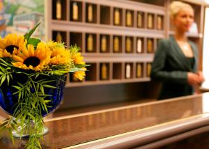 un jarrón de flores amarillas en un mostrador con una mujer en Hotel Deutsches Theater en Múnich