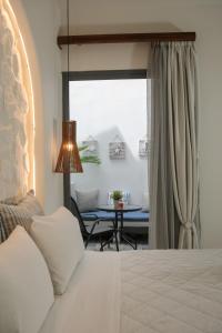 a bedroom with a bed and a table and a window at Naxos Petite Studios in Agios Prokopios
