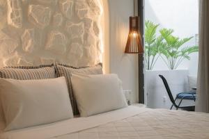 a bed with white pillows and a stone wall at Naxos Petite Studios in Agios Prokopios