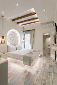 a white bedroom with a bed and a large window at Naxos Petite Studios in Agios Prokopios