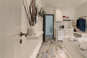 a white living room with a couch and a kitchen at Naxos Petite Studios in Agios Prokopios