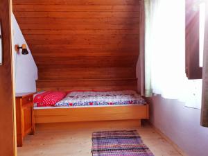 a small bed in a wooden room with a window at Waldheimat in Fresach