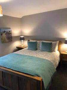 a bedroom with a large bed with blue pillows at Blue Sky Cottage in Matlock