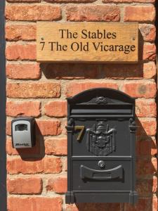 a brick wall with a black mailbox and a sign at The Stables at the Old Vicarage in Lincoln