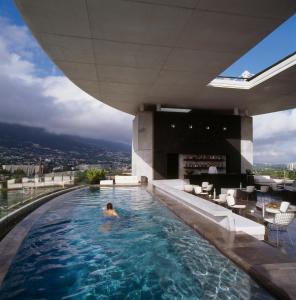 a man in a swimming pool on the roof of a building at Habita Monterrey, a Member of Design Hotels in Monterrey