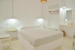 a white bedroom with a white bed and a mirror at Veletas Apartments in Adamantas
