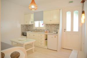 a kitchen with white cabinets and a table and a door at Veletas Apartments in Adamantas