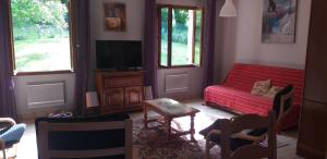 Saint-Amand-en-PuisayeにあるLa Griotterieのリビングルーム(赤いソファ、テレビ付)