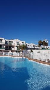 une grande piscine en face d'un bâtiment dans l'établissement Lanzarote-Beach-Apartment, Las Cucharas Beach, Costa Teguise -- 1 MINUTE WALK FROM MAIN SQUARE, 35 METERS FROM BEACH, à Costa Teguise