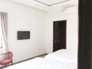 a bedroom with two beds and a tv on the wall at Motel Thanh Long in Danang