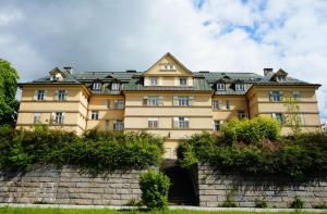 un grand bâtiment jaune au-dessus d'un mur de briques dans l'établissement Arnie Apartman, à Arnoldstein