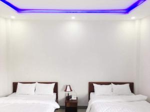 two beds in a room with a blue ceiling at Motel Thanh Long in Danang