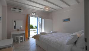a bedroom with a bed and a table and a window at Nostos Beachfront Apartments & Studios in Agios Ioannis Tinos