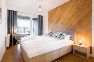 um quarto com uma cama grande e uma cabeceira em madeira em Apartments Poznań Niedziałkowskiego by Renters em Poznań